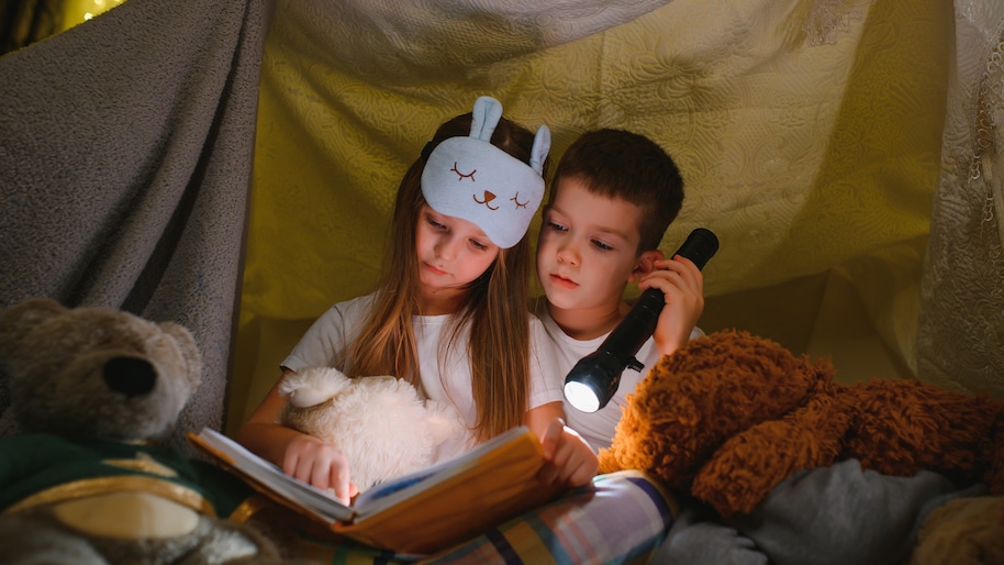 two-children-with-flashlight-read-a-book