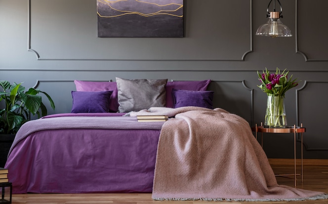 Bett im Schlafzimmer mit violetter Bettwäsche